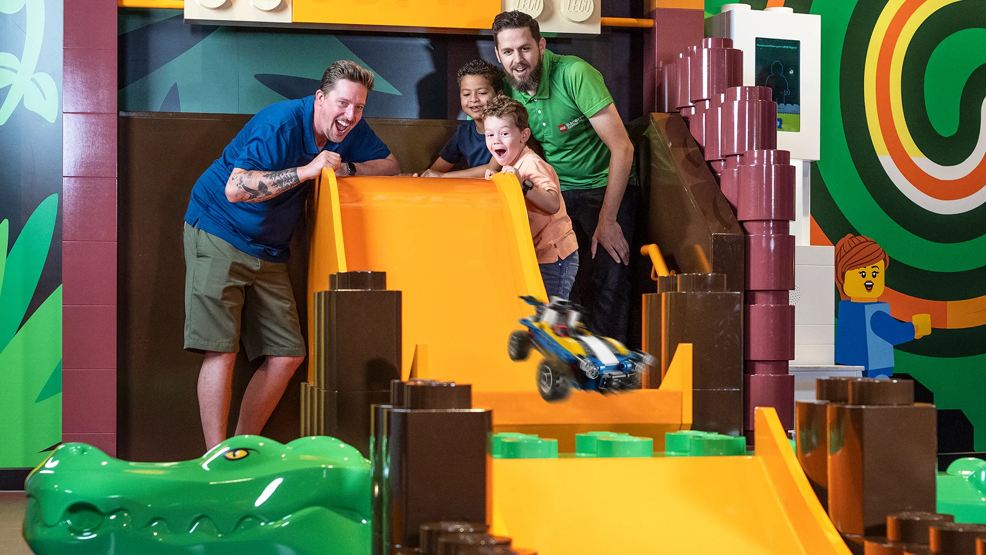 Kids race a LEGO® car down a slide at LEGOLAND® Discovery Center Boston.